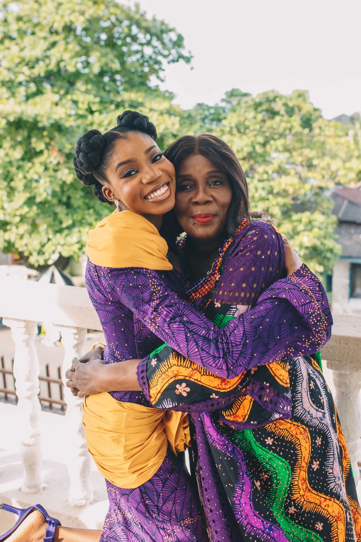 adeilé hugging an older woman in purple and gold on the veranda