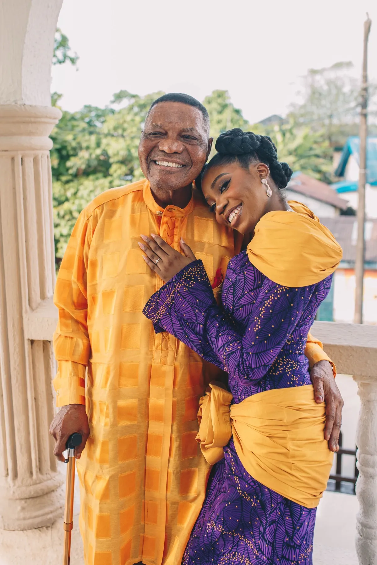 adeilé leaning into an older man in a gold agbada