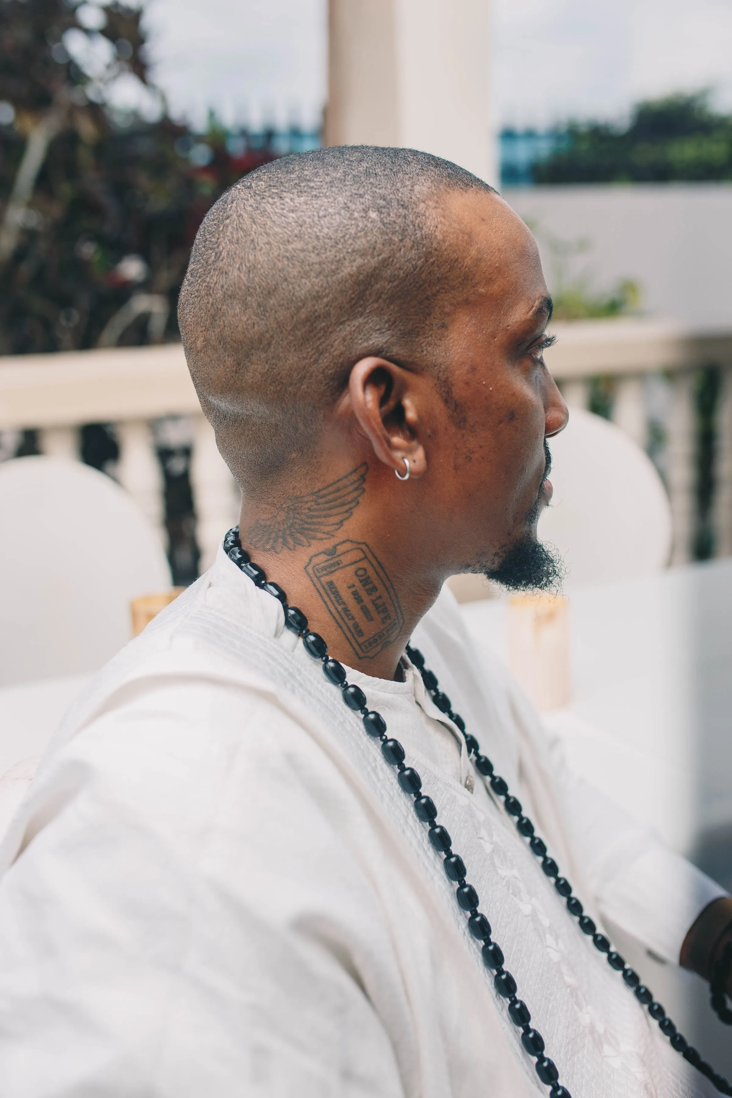 ekanem in white with dark beads, seen from behind, black and white