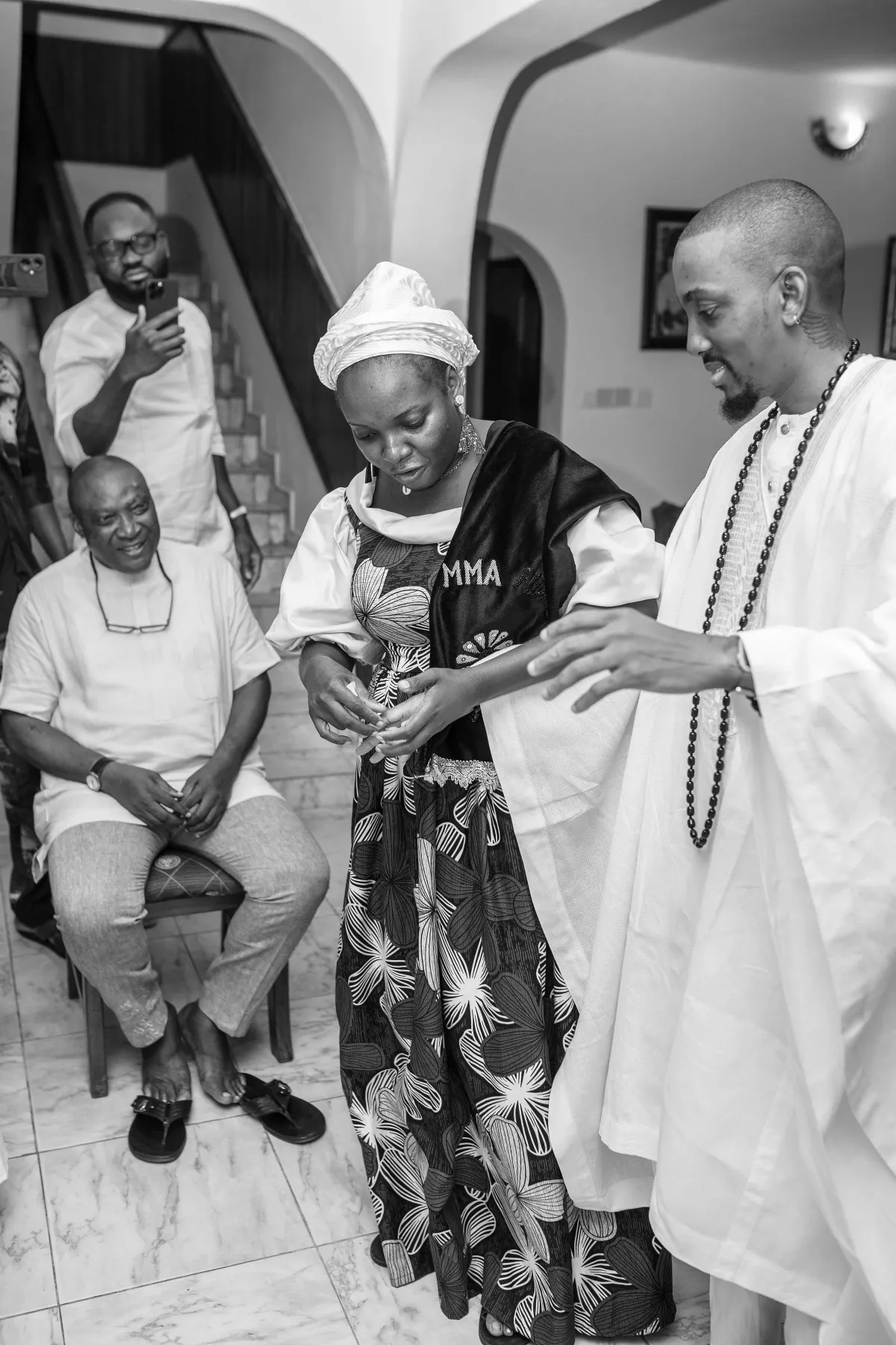 an elder blessing adeilé while ekanem looks on, black and white