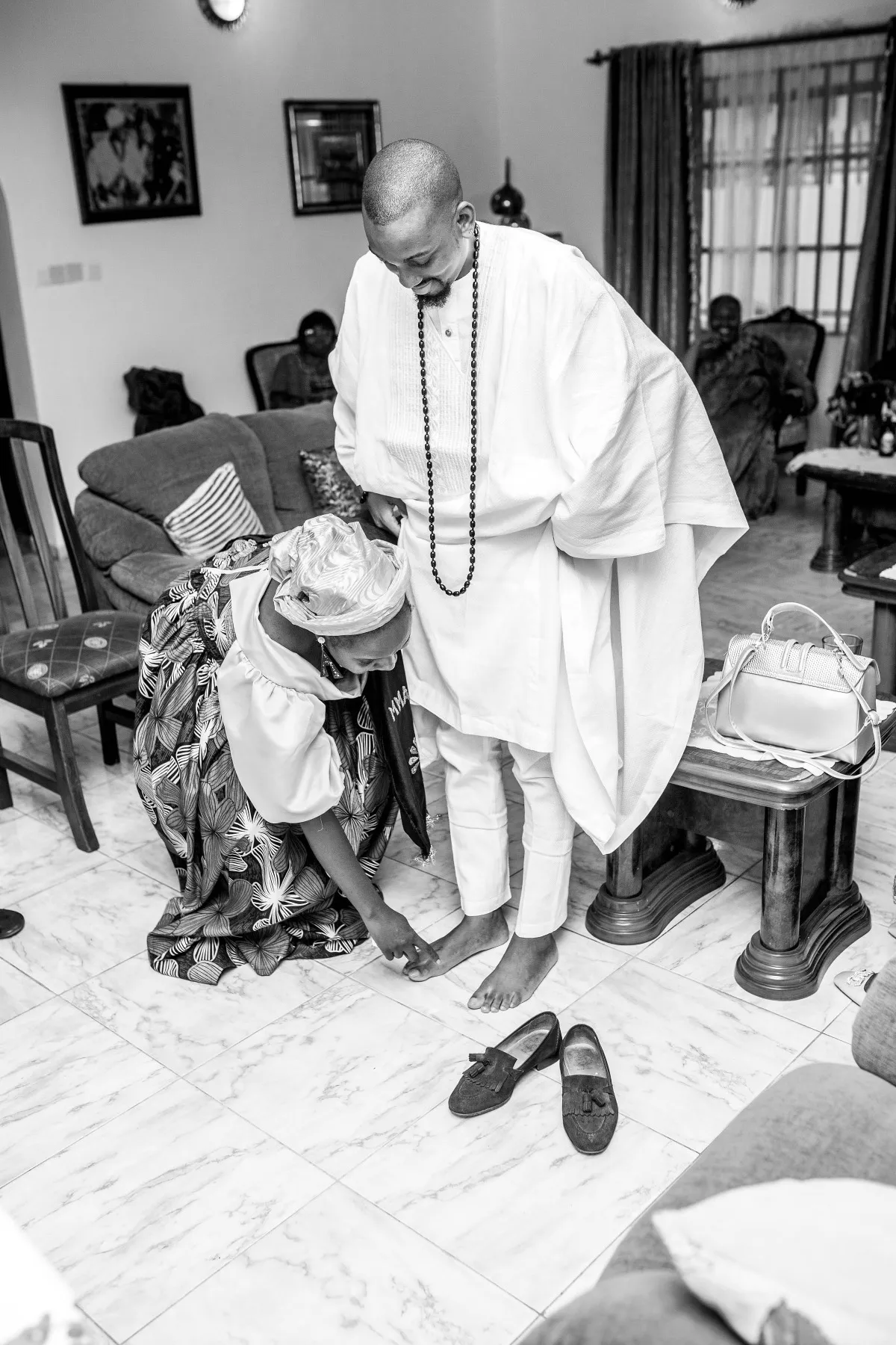 ekanem standing over adeilé as she kneels, black and white