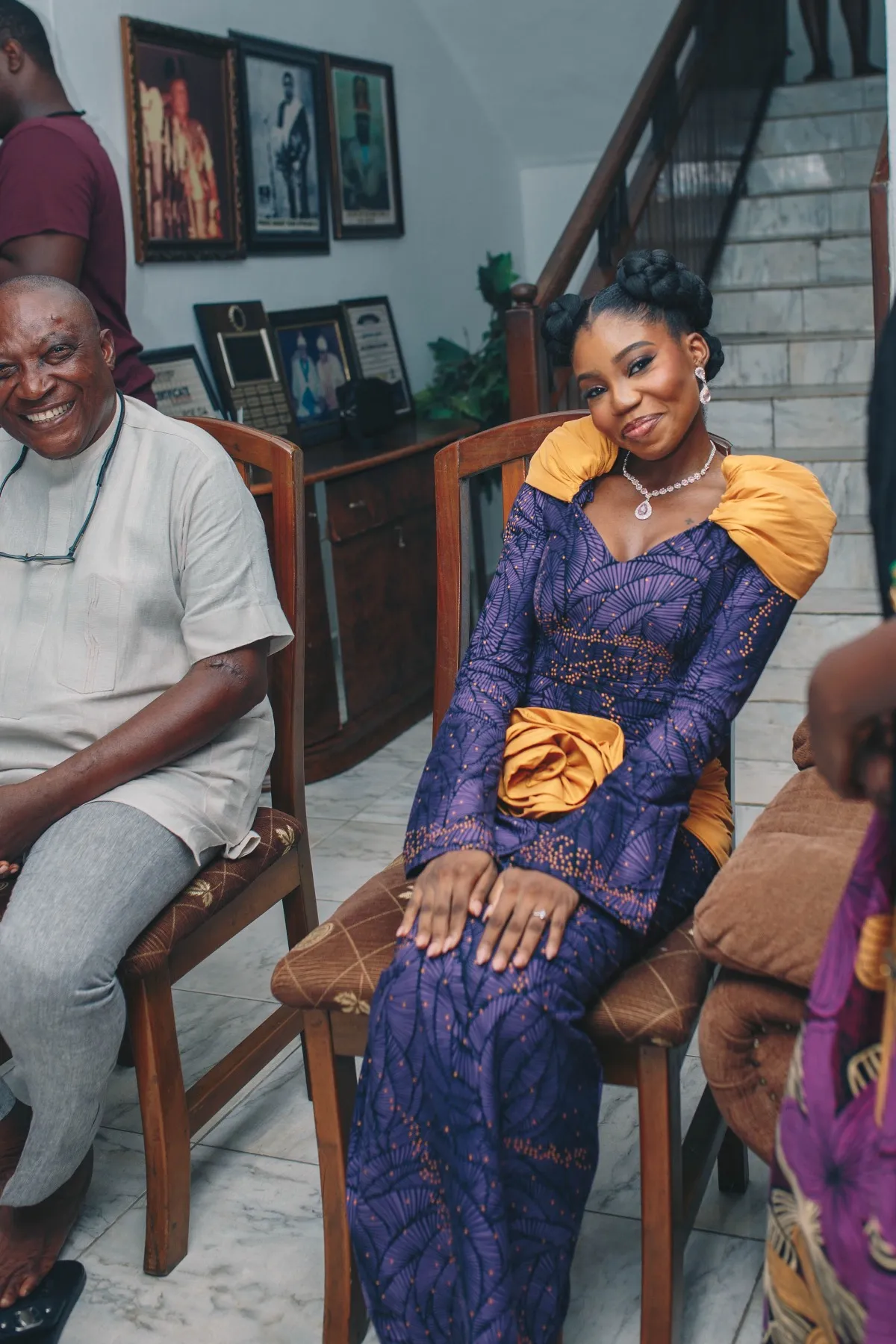 adeilé seated in purple and gold, smiling